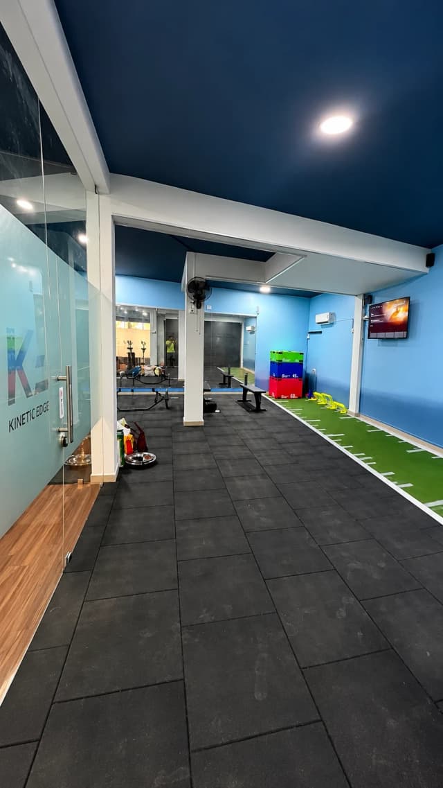 The Kinetic Edge training floor in Mogappair East — the turf acceleration lane, plyometric boxes and the strength area beyond the entrance